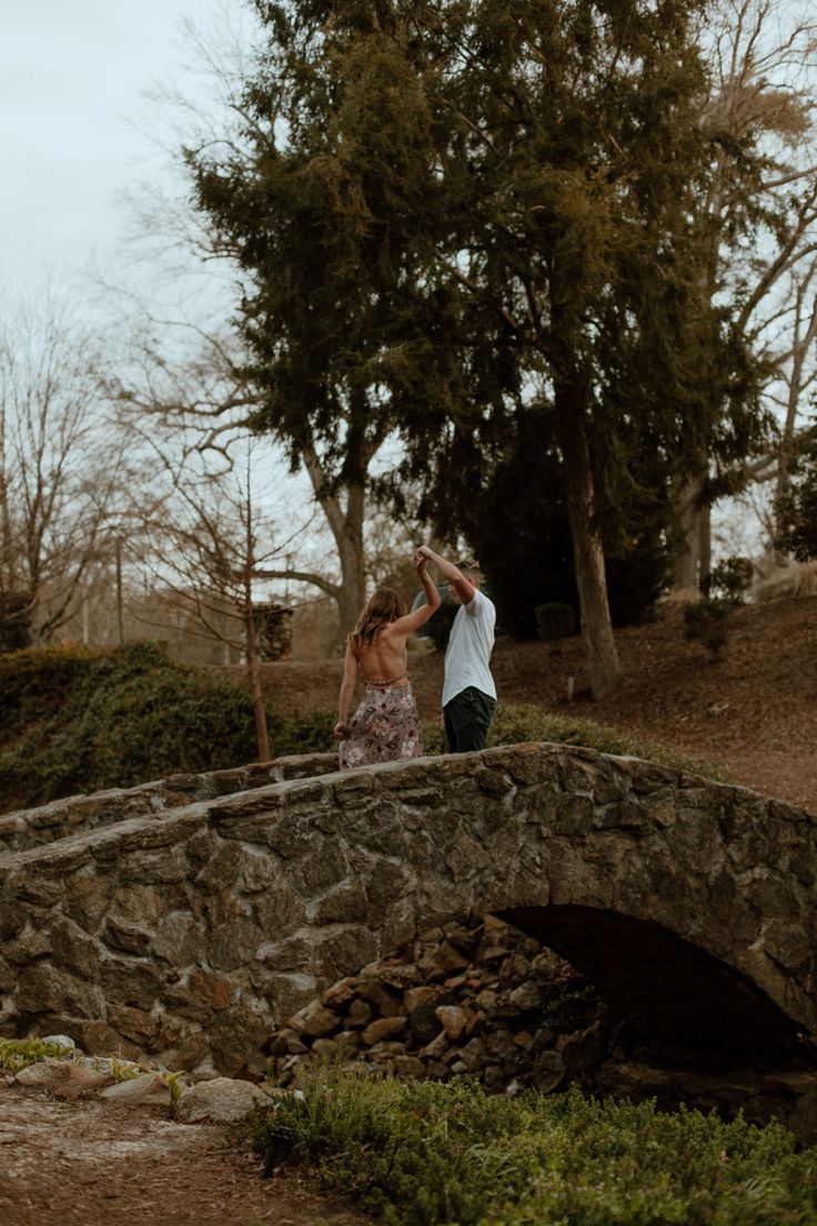 a man and woman standing on a stone bridge