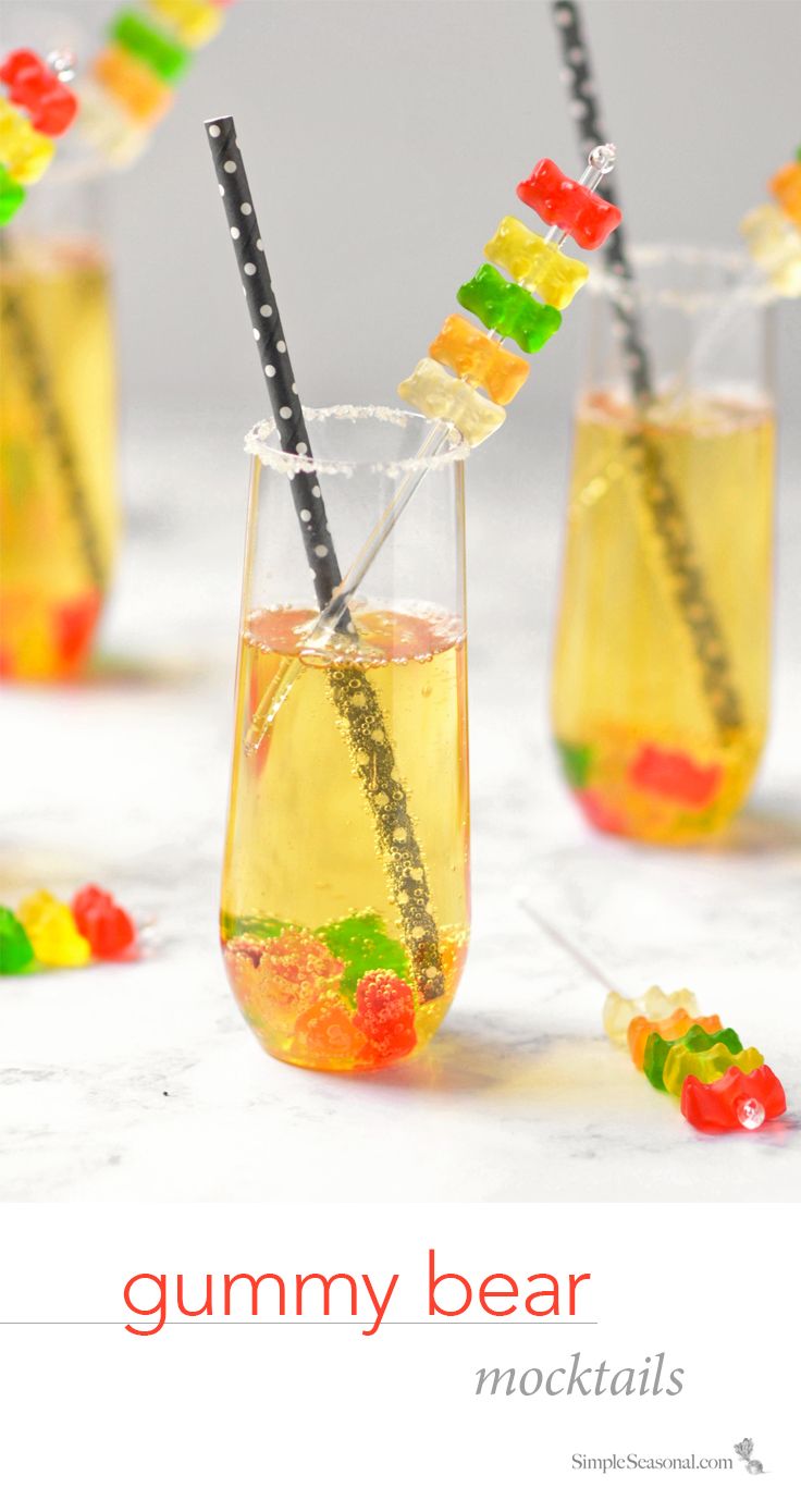 four glasses filled with gummy bears and straws on top of a table next to candy sticks