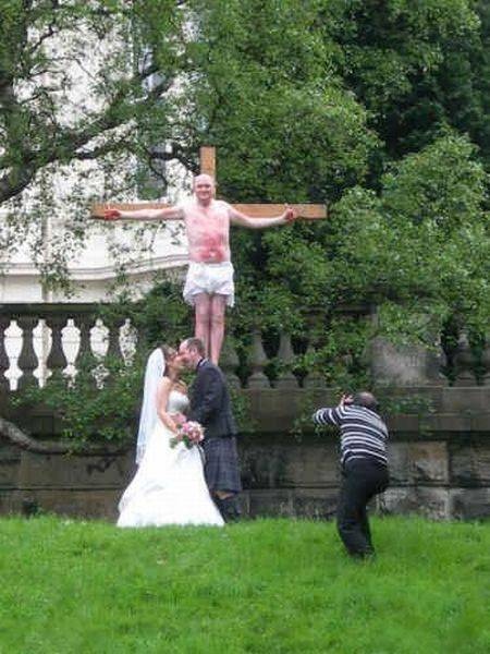 a man and woman standing on top of a wooden cross in the grass next to each other