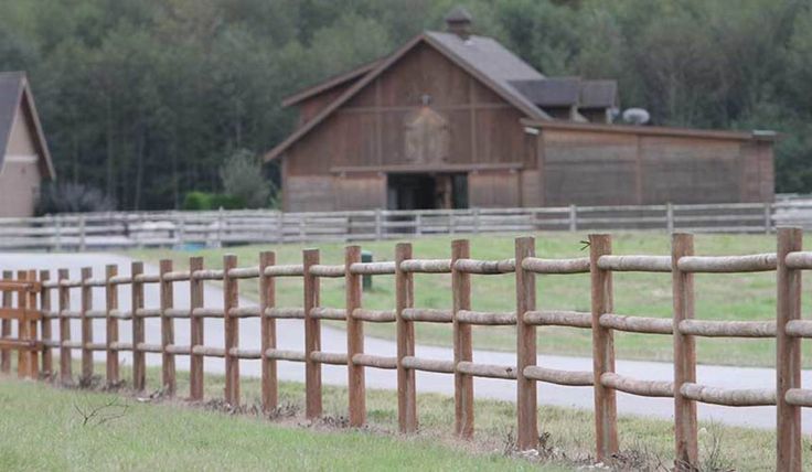 a wooden fence in front of a barn