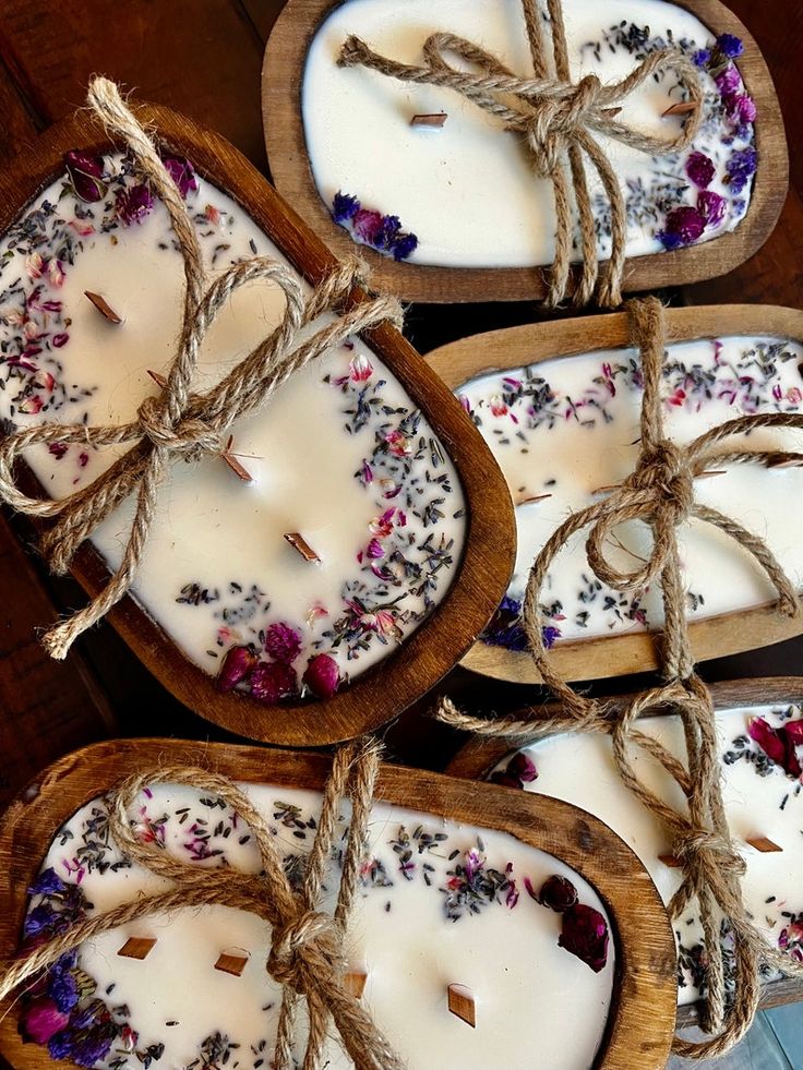 four wooden trays filled with white candles tied up to twine and decorated with flowers