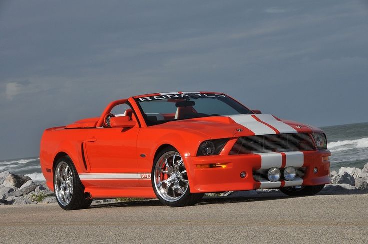 an orange sports car parked on the beach