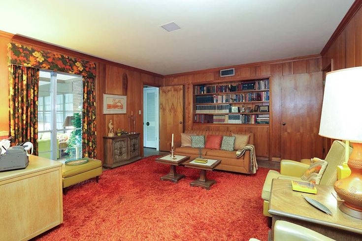 a living room with wood paneling and red carpeted flooring is pictured in this image