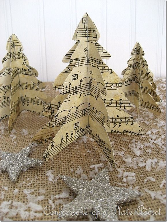 three christmas trees made out of sheet music are sitting on a burlap surface