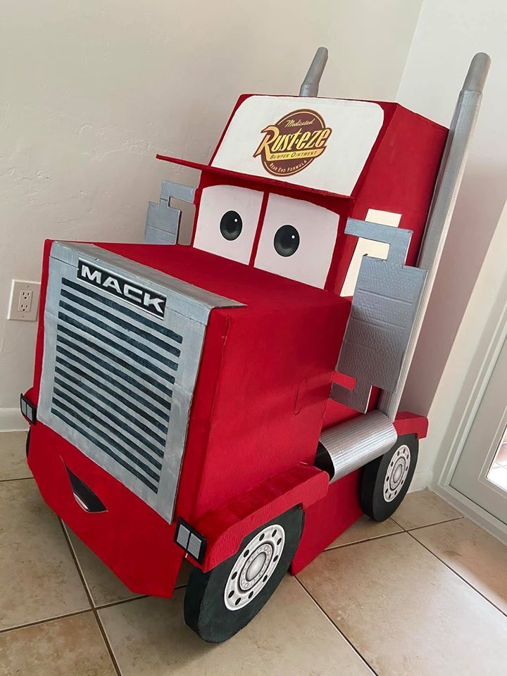 a red truck costume sitting on top of a tile floor next to a white wall