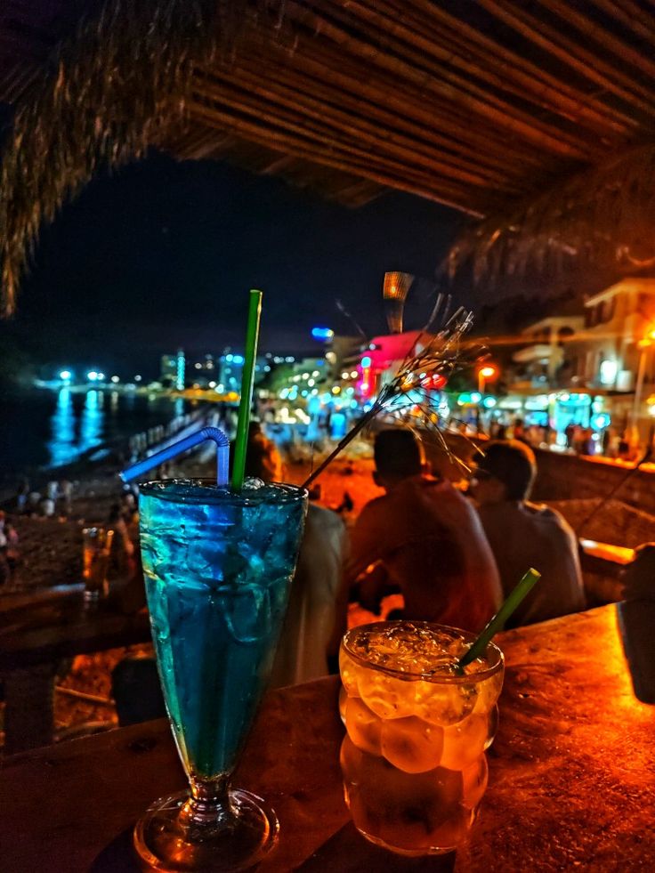 two drinks sitting on top of a table next to each other in front of a bar