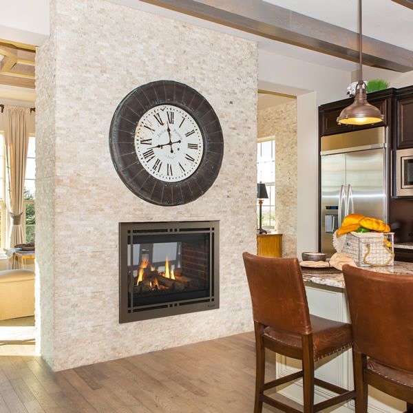 a large clock mounted to the side of a wall above a fire place in a kitchen