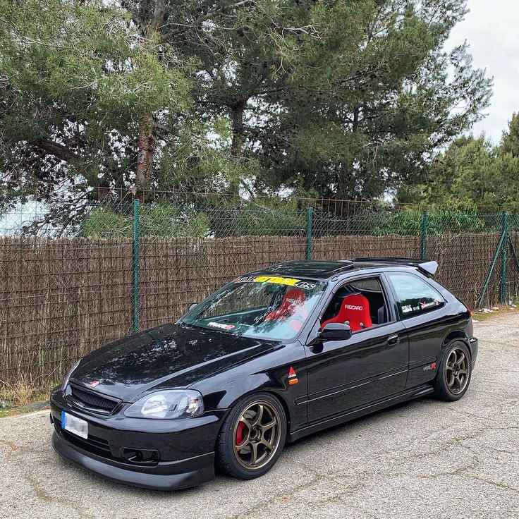 a black car parked in front of a fence