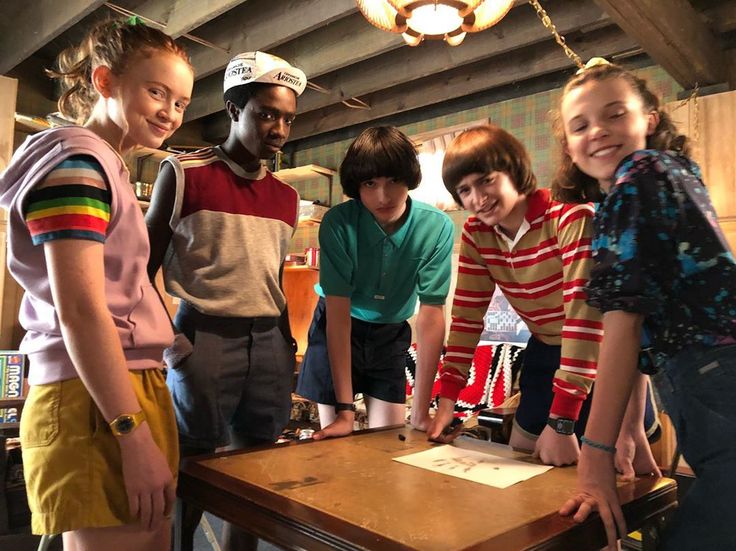 a group of young people standing around a wooden table