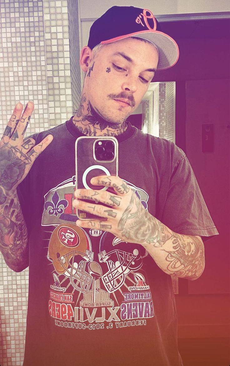 a man taking a selfie with his cell phone in front of him and tattoos on his arms