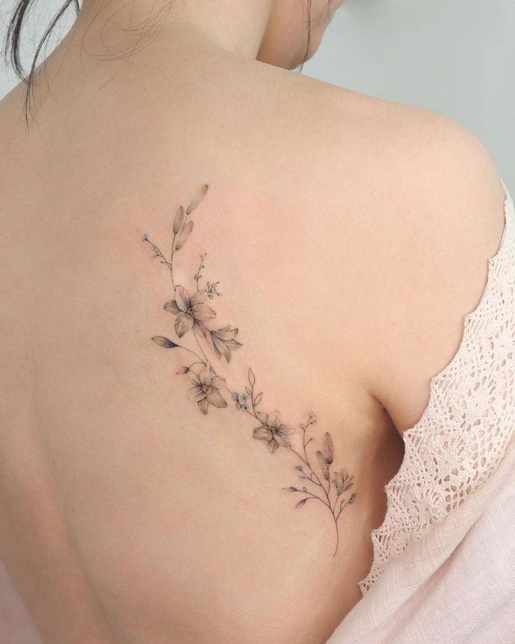 the back of a woman's shoulder with flowers and leaves on her left side