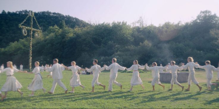 a large group of people in white clothes are running through the grass with trees behind them