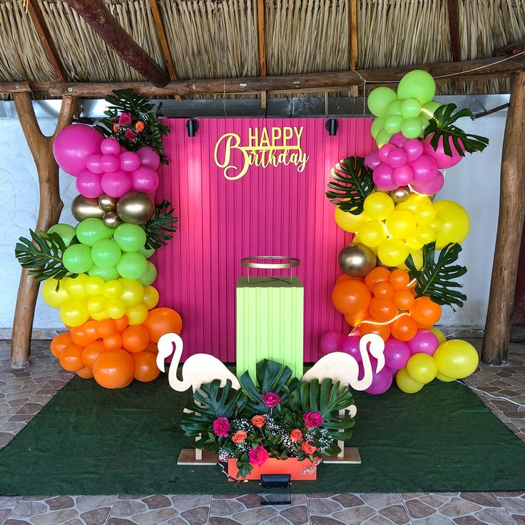 a tropical themed birthday party with flamingos, balloons and streamers on the stage