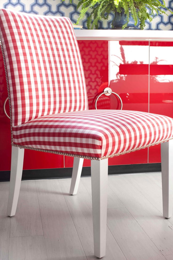 a red and white checkered chair sitting in front of a potted plant on a table