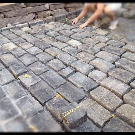 a man is laying bricks on the ground