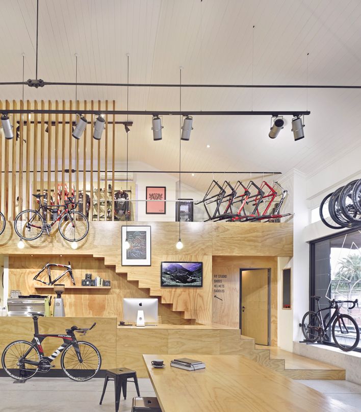 the inside of a bike shop with lots of bikes hanging from the ceiling and wooden shelves