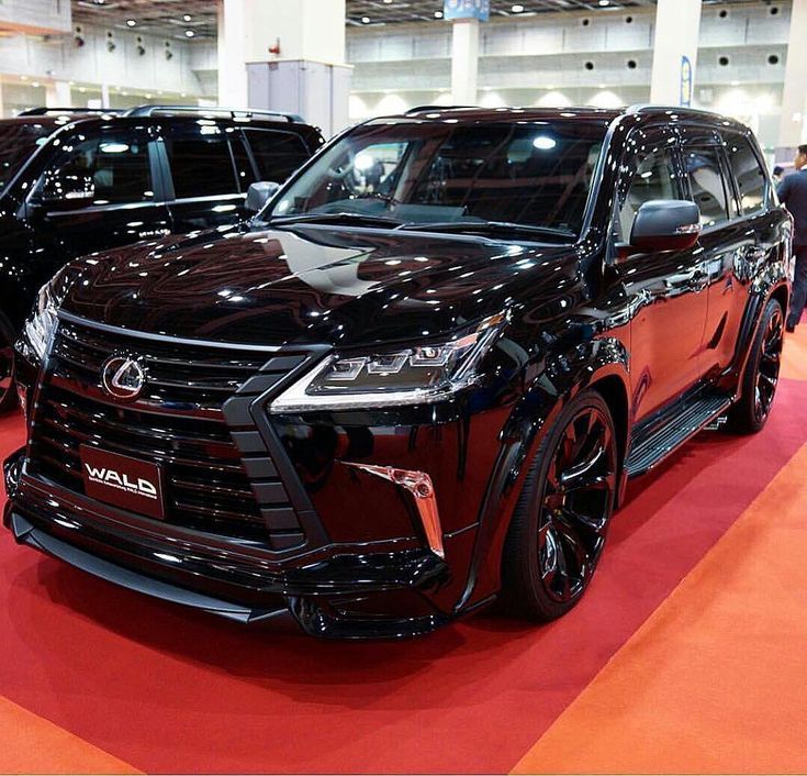 two suvs on display at an auto show, one is red and the other is black