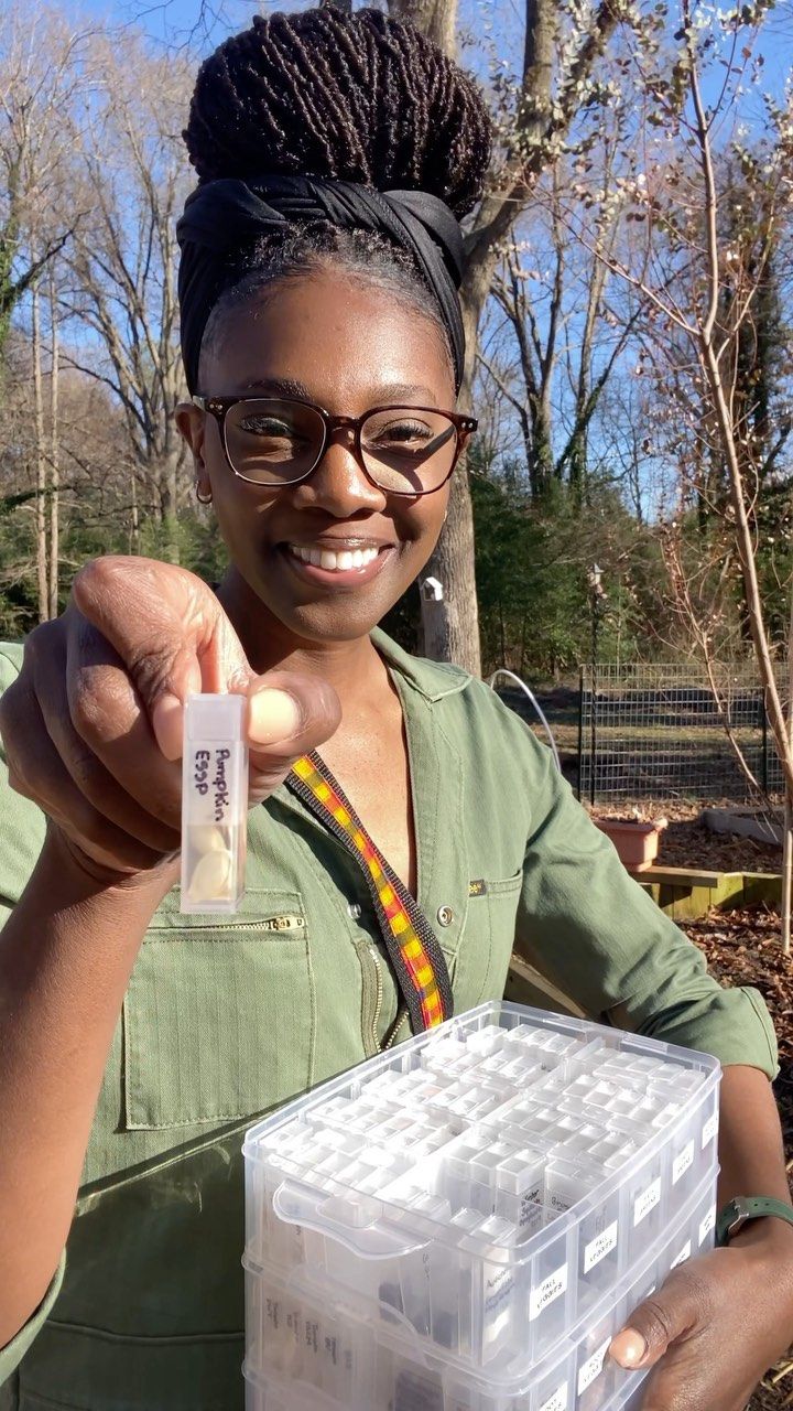 a woman holding up a plastic container filled with small containers in front of some trees