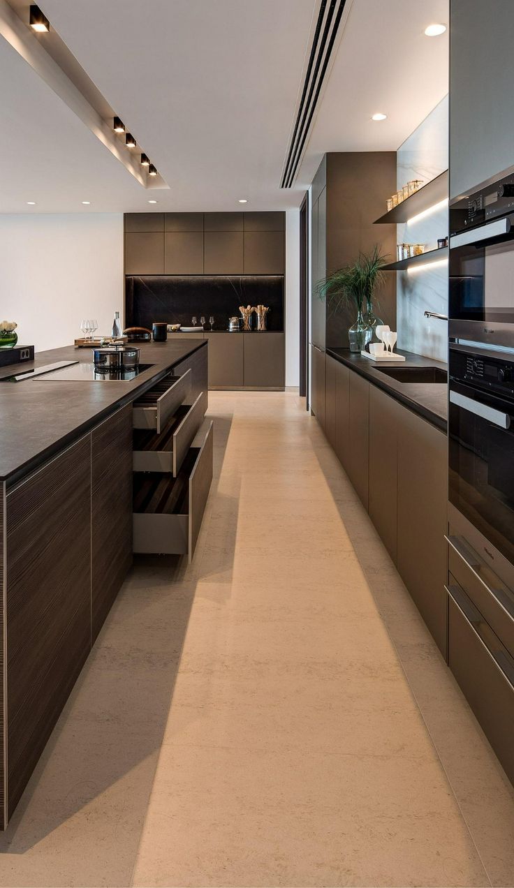 a long kitchen with stainless steel appliances and counter tops, along with an island in the middle