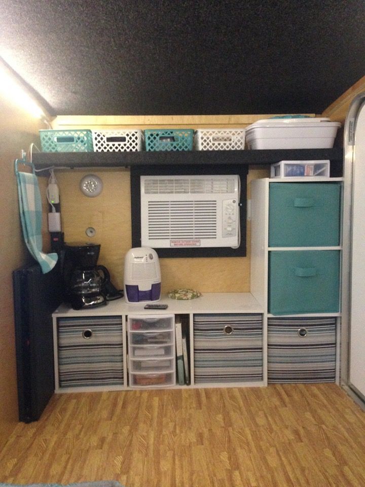 a small room with some drawers and shelves on the wall next to an air conditioner