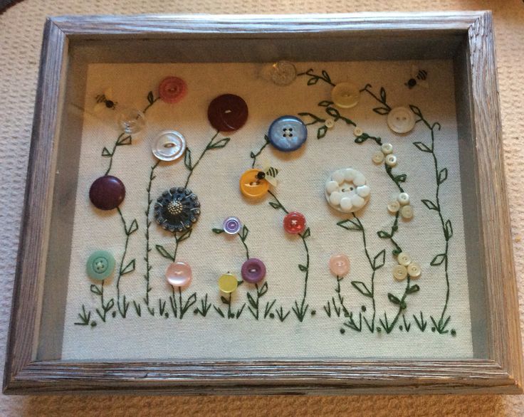 a shadow frame with buttons and flowers in it