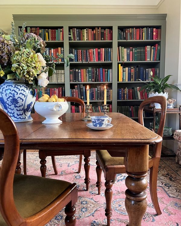 a dining room table and chairs with bookshelves in the background