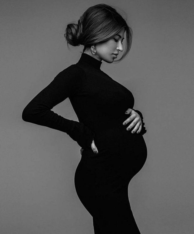 a pregnant woman poses in a black dress