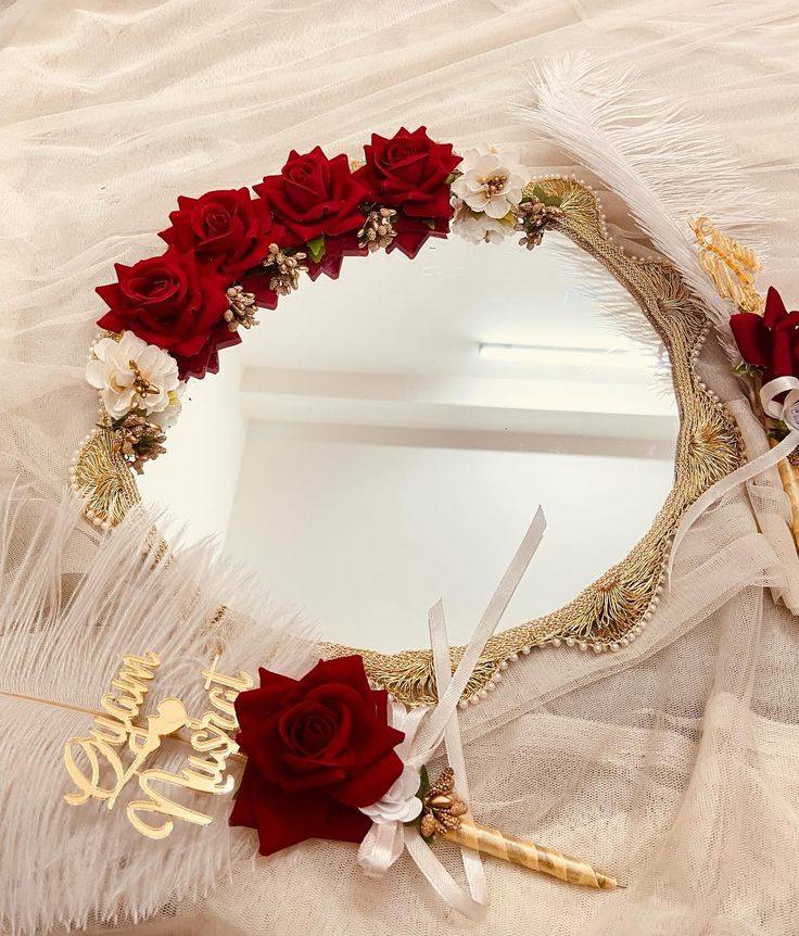 there is a mirror with flowers and feathers on the table next to it, as well as some scissors