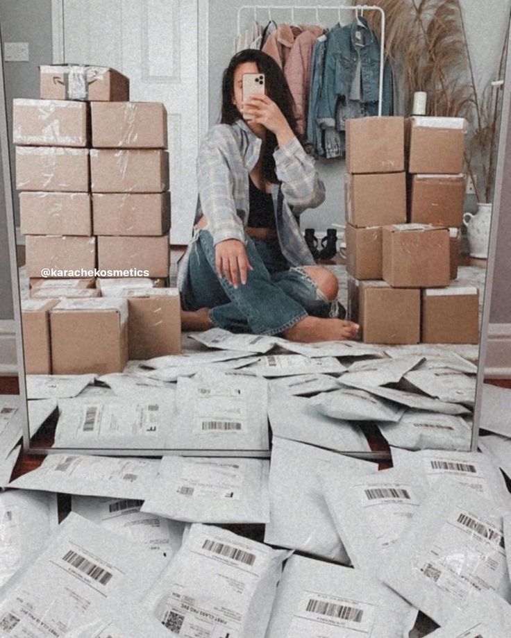 a woman sitting on the floor in front of a mirror surrounded by boxes and mail