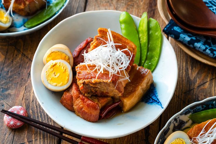 two plates with food on them and chopsticks next to one plate that has an egg in it