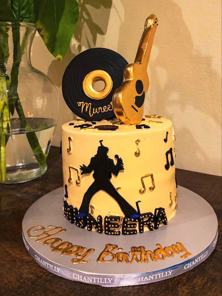 a birthday cake decorated with musical notes and a golden guitar on top is sitting on a table