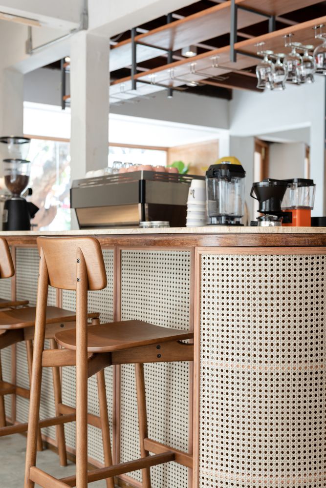 two wooden chairs sitting in front of a counter with coffee maker and cups on it