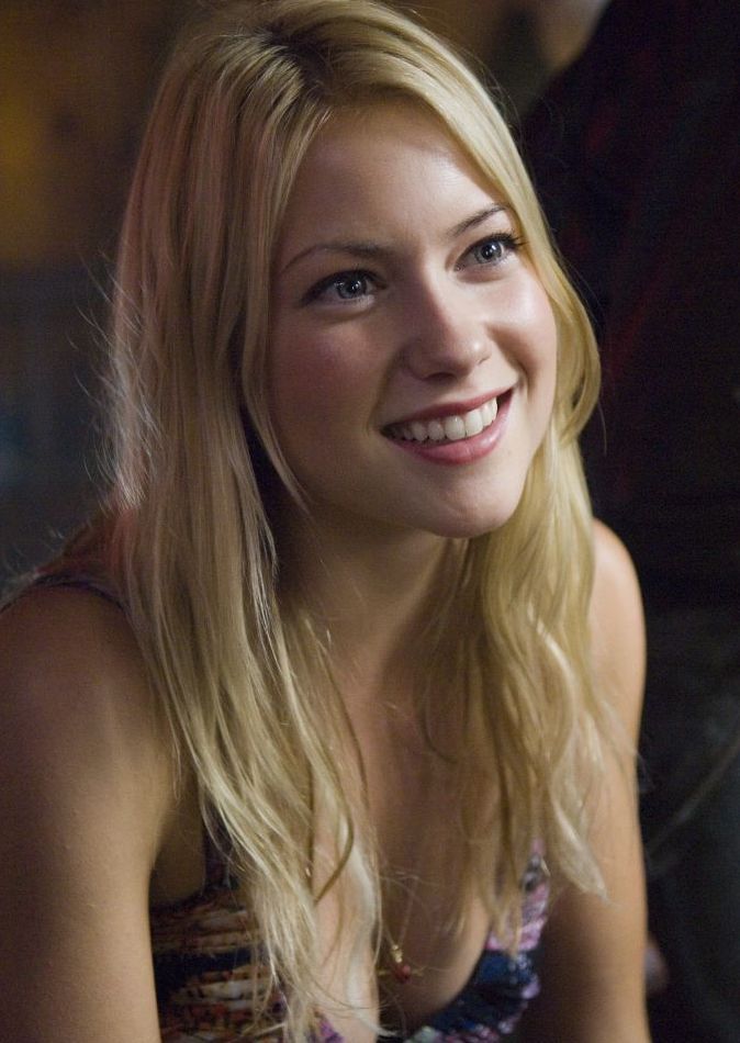 a beautiful blond woman sitting down smiling at the camera