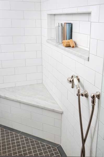 a white tiled shower with two hand held shower heads