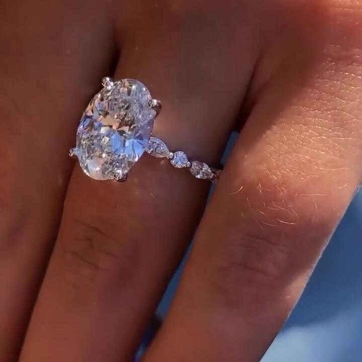 a woman's engagement ring with an oval diamond in the center and side stones