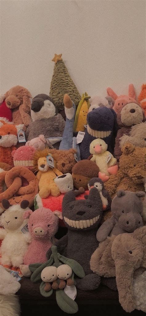 a pile of stuffed animals sitting next to each other on a table in front of a white wall