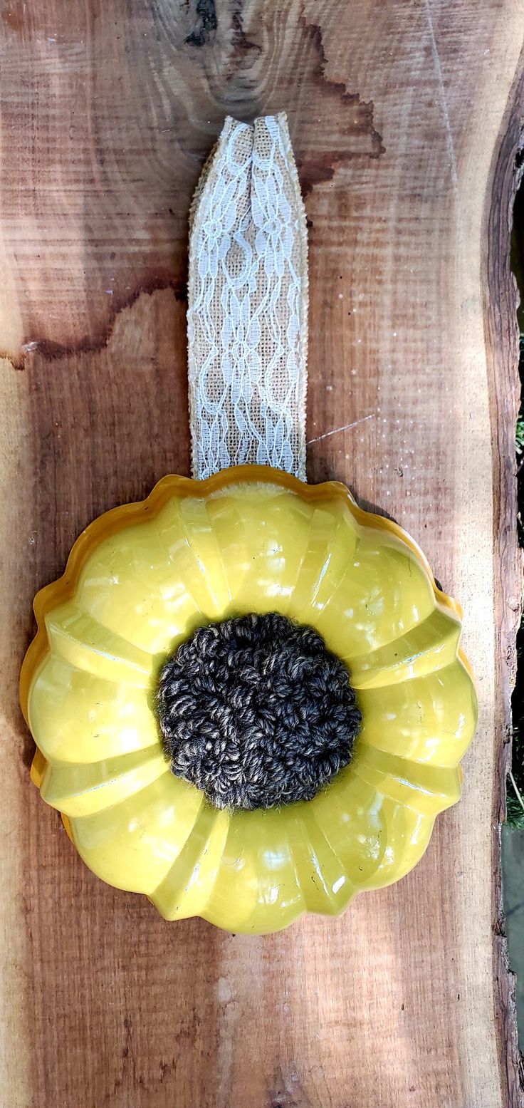 a yellow flower with black seeds in it on a piece of wood next to lace