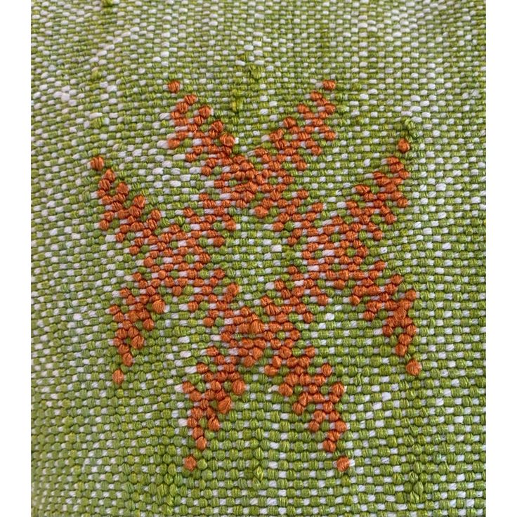 an orange flower is embroidered on a green cloth with red flowers in the center and bottom