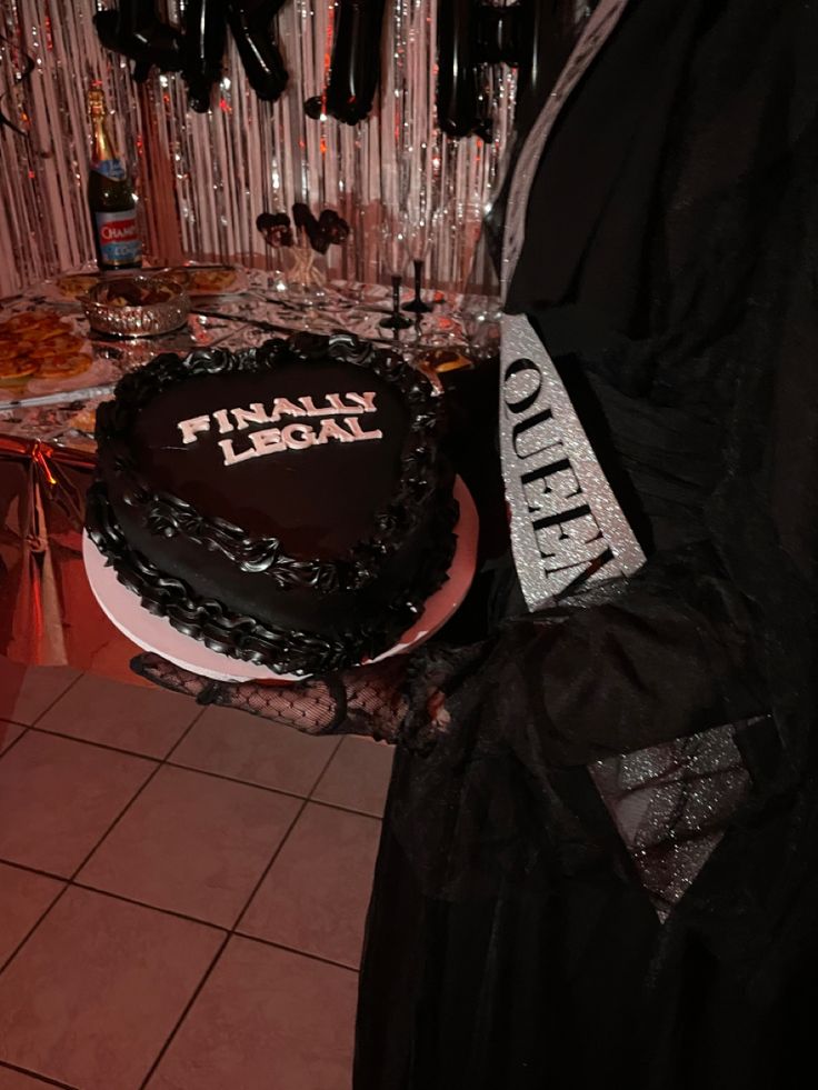 a person holding a cake in front of a table with balloons and streamers on it