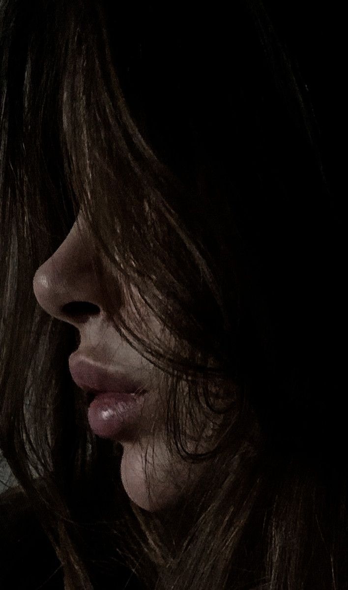 a close up of a woman's face in the dark with her hair blowing back