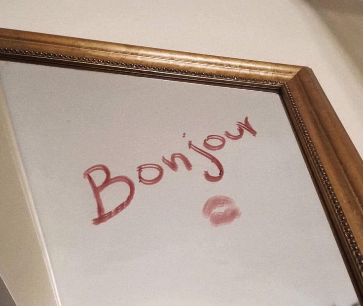 a framed photograph with the word bonjou written in red ink on white paper next to a brown frame