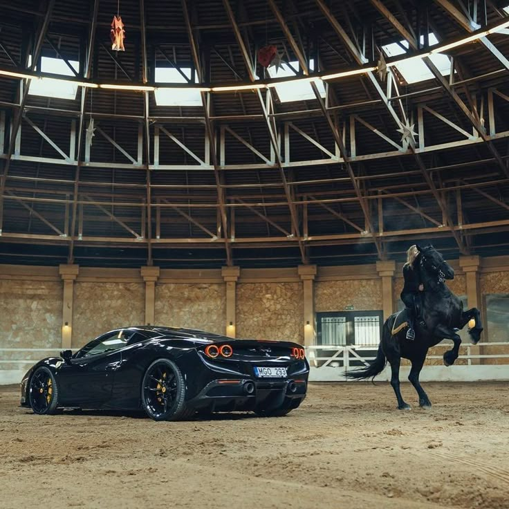 a black sports car and a horse in an arena