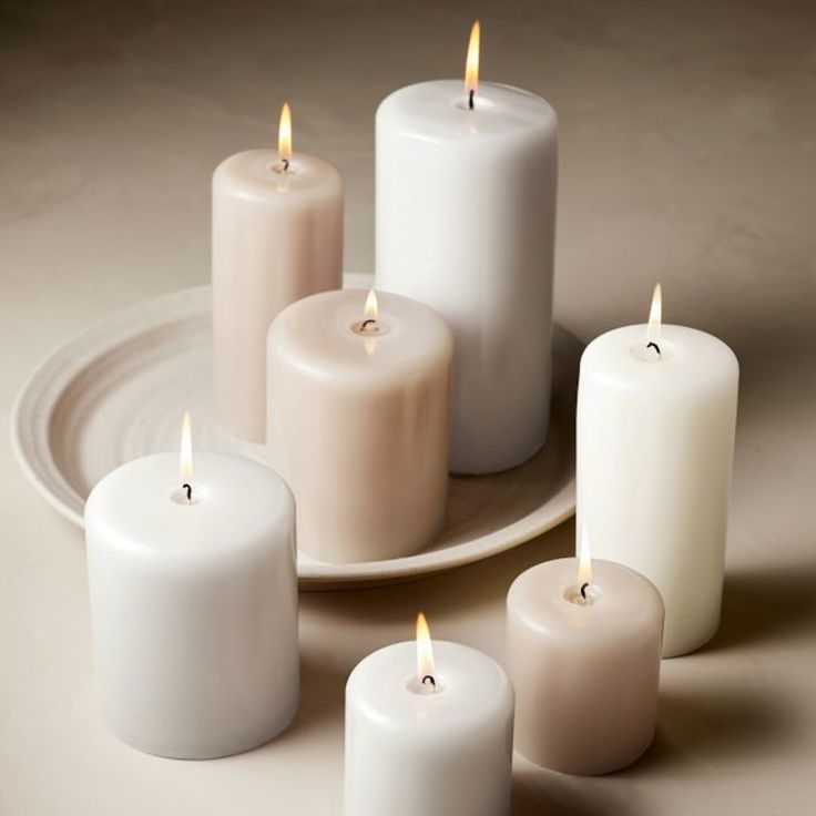 five white candles on a plate with one lit