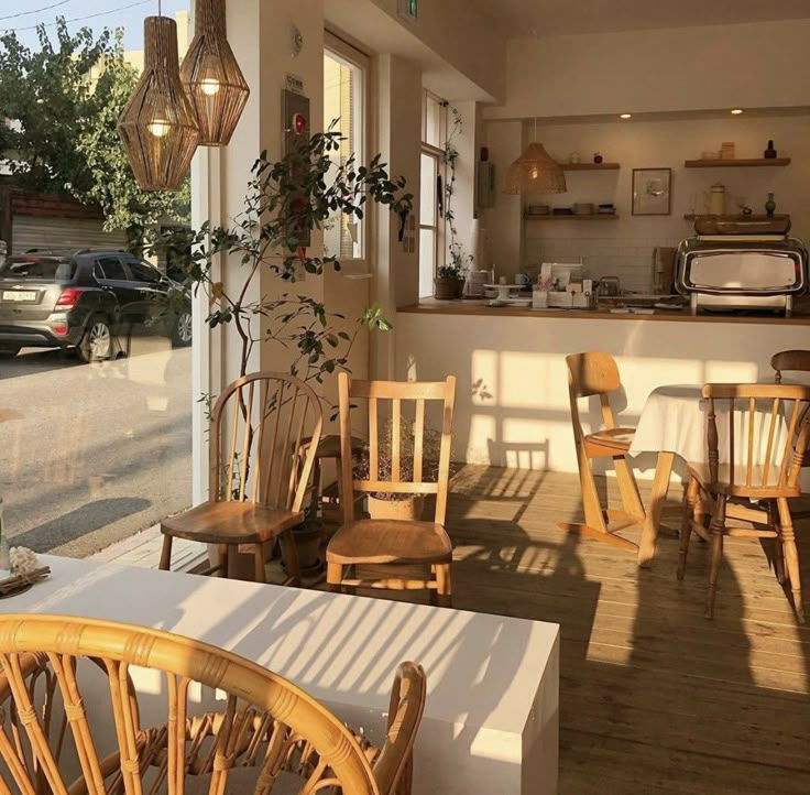 the inside of a restaurant with wooden chairs and tables in front of an open window