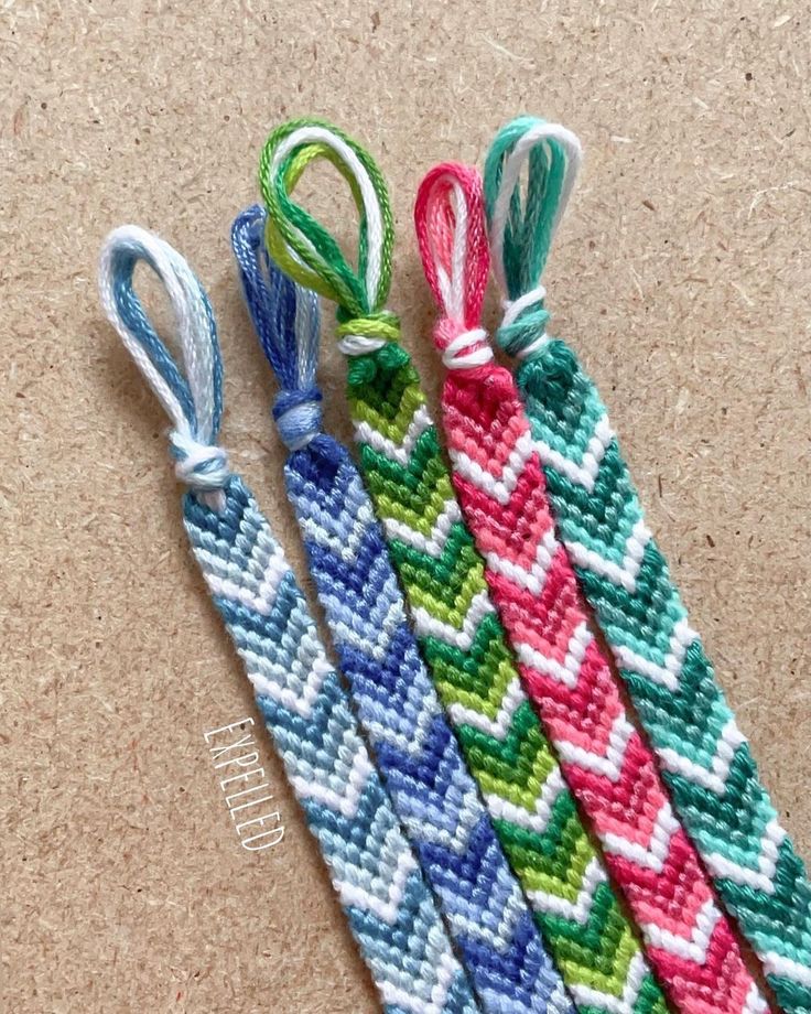 three different colored braided bracelets sitting next to each other on a table top