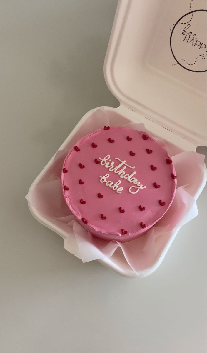 a pink birthday cake in a box with the words happy birthday on it's side