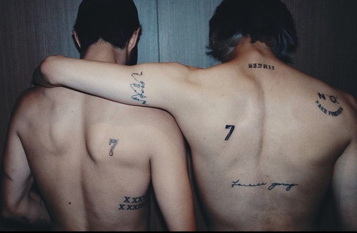 two men with tattoos on their backs