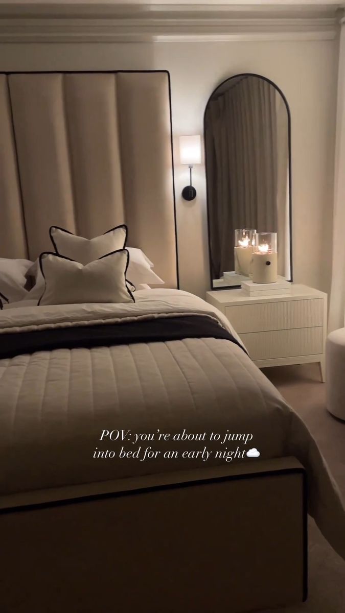 a bedroom with a bed, mirror and two candles on the nightstands in front of it