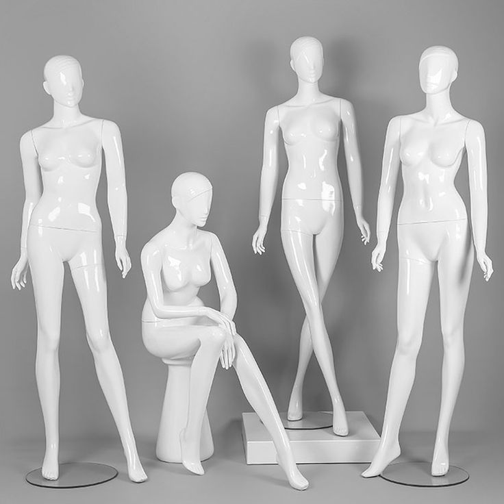 three white mannequins sitting on pedestals in front of a gray background