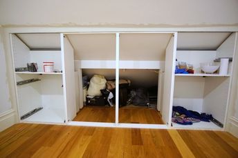 an empty room with wooden floors and white closets on the wall, filled with items